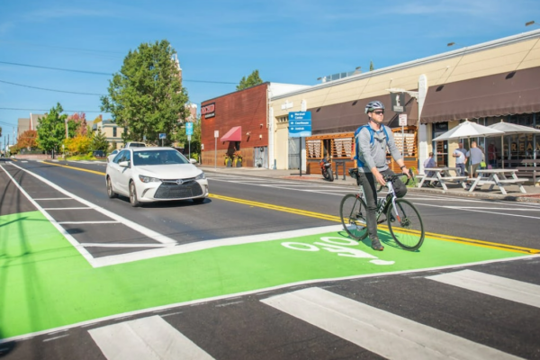 Bike in green bike line in front of a car