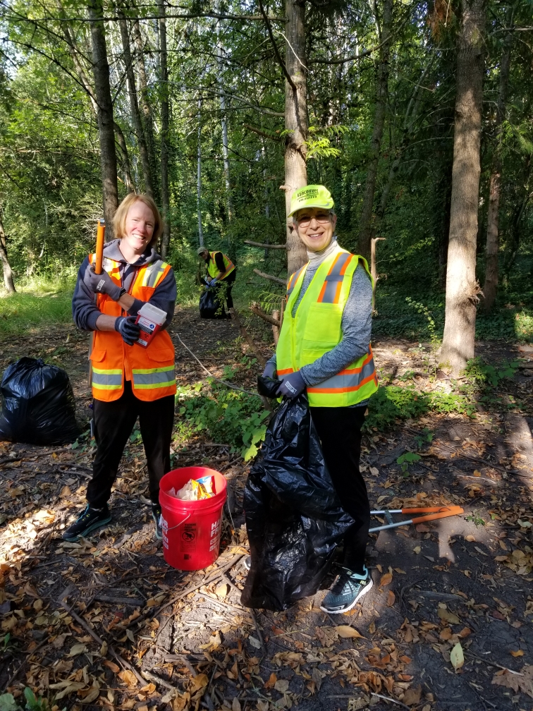 Volunteers with safety vests picking up litter in a forest