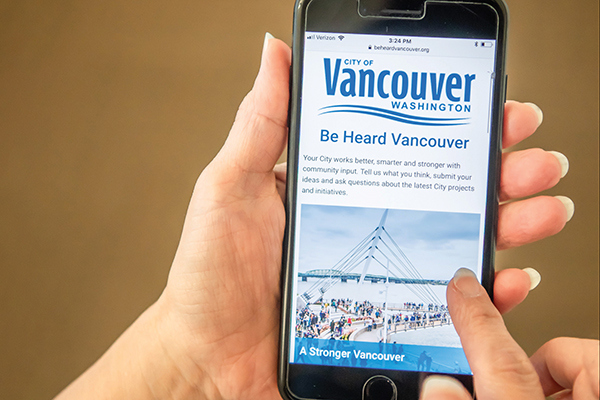 Phone with Be Heard Vancouver website on screen