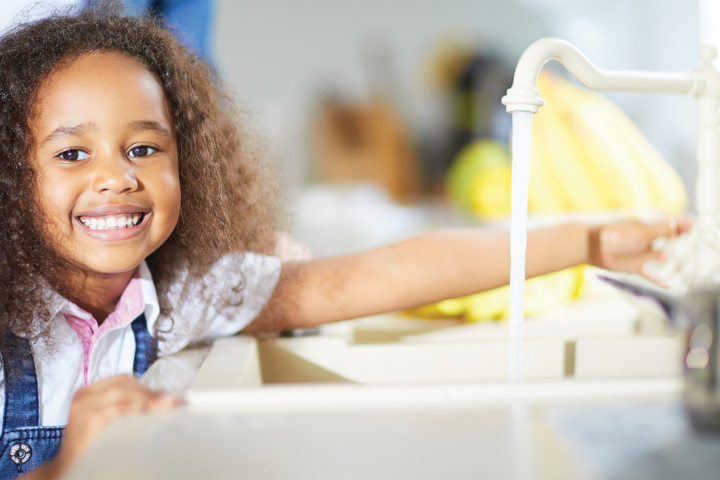 Girl running water at sink