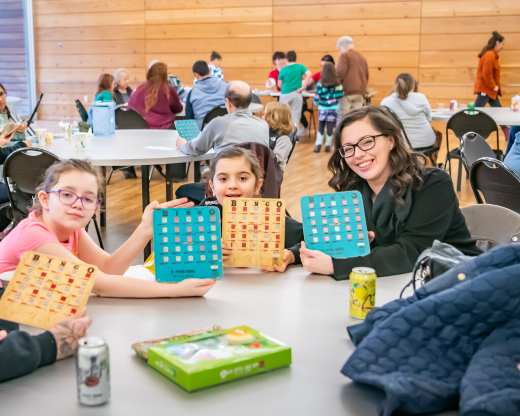 Family smiles while they hold up their Bingo cards at Firstenburg Center Bingo Night