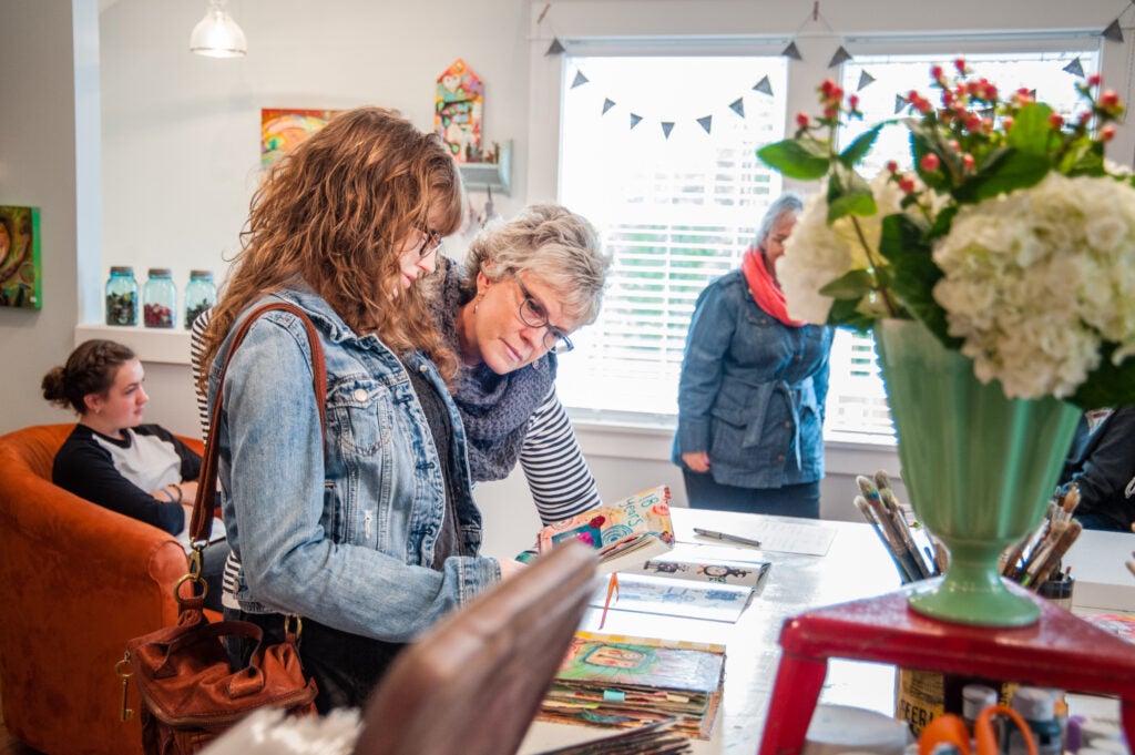 Two people looking through booklets during an open studios tour.