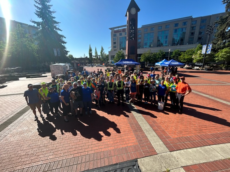 large group of volunteers pose on brick plaza with the clock tower in the background