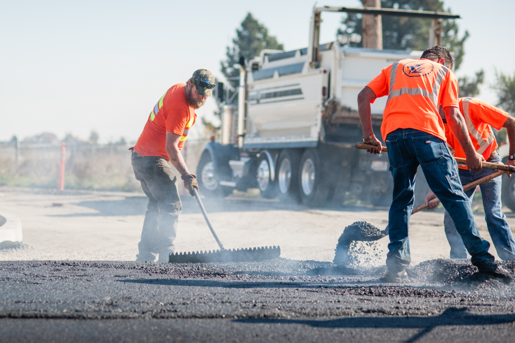 Crews spreading out hot mix asphalt as part of resurfacing street work