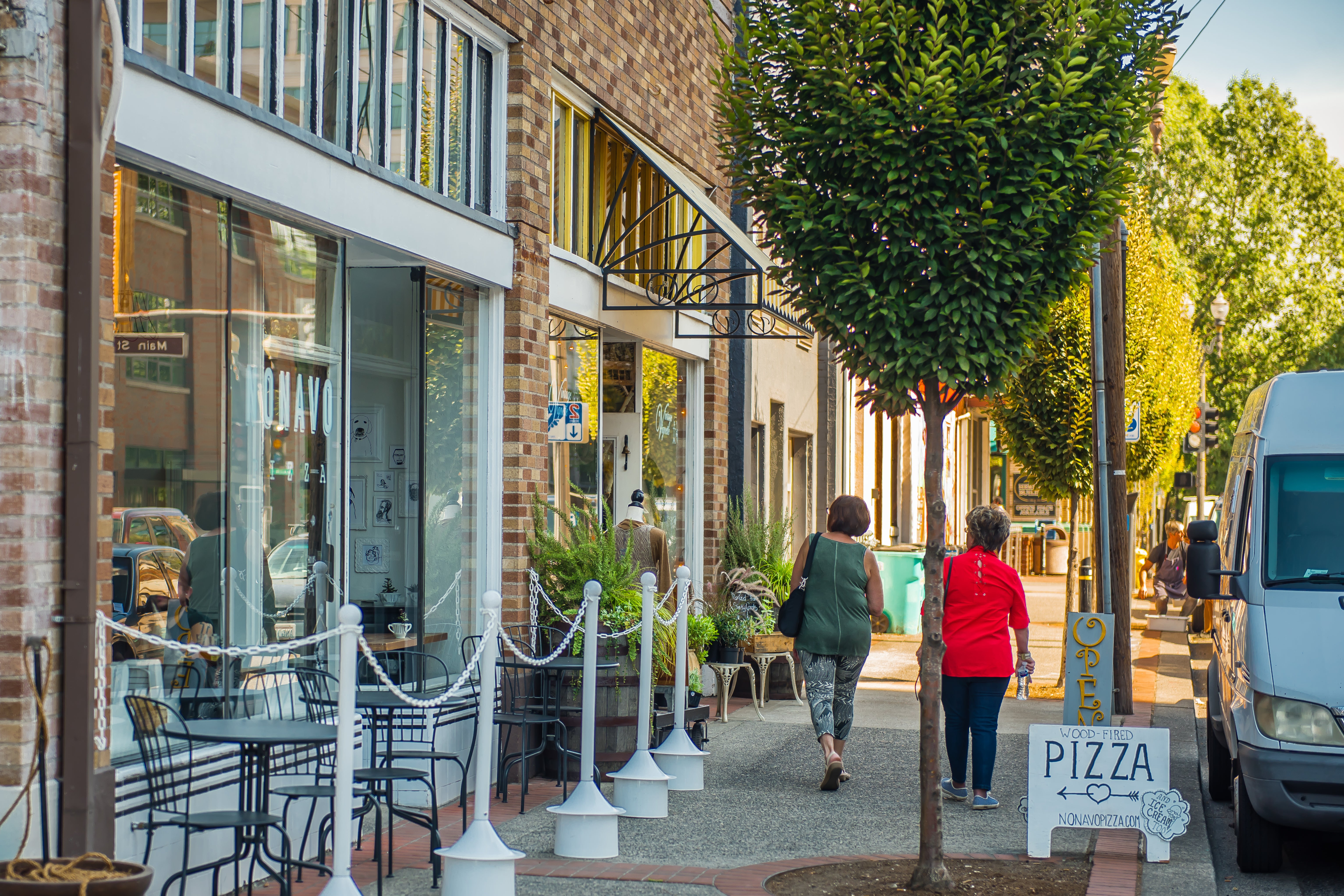 Two people walking down 6th Street downtown by local small businesses.