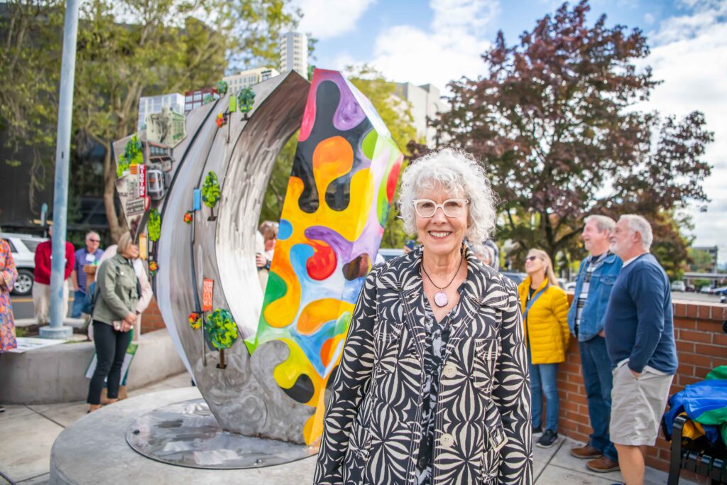 Artist Sharon Agnor stands in front of “Vounteer Corner” a public art piece installed downtown in 2024 to honor the collective contributions of volunteers