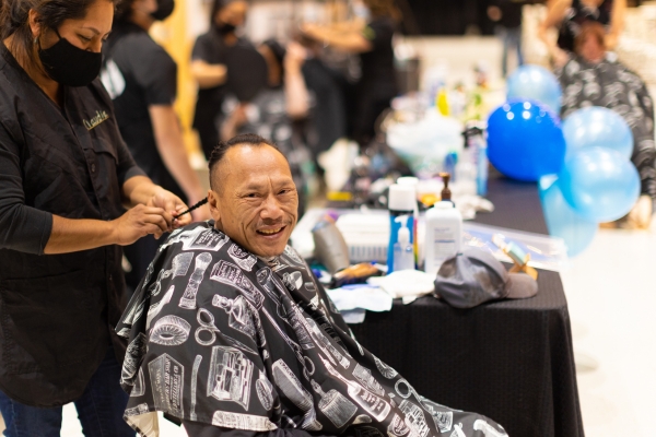 Unsheltered individual receives a haircut at a resource fair