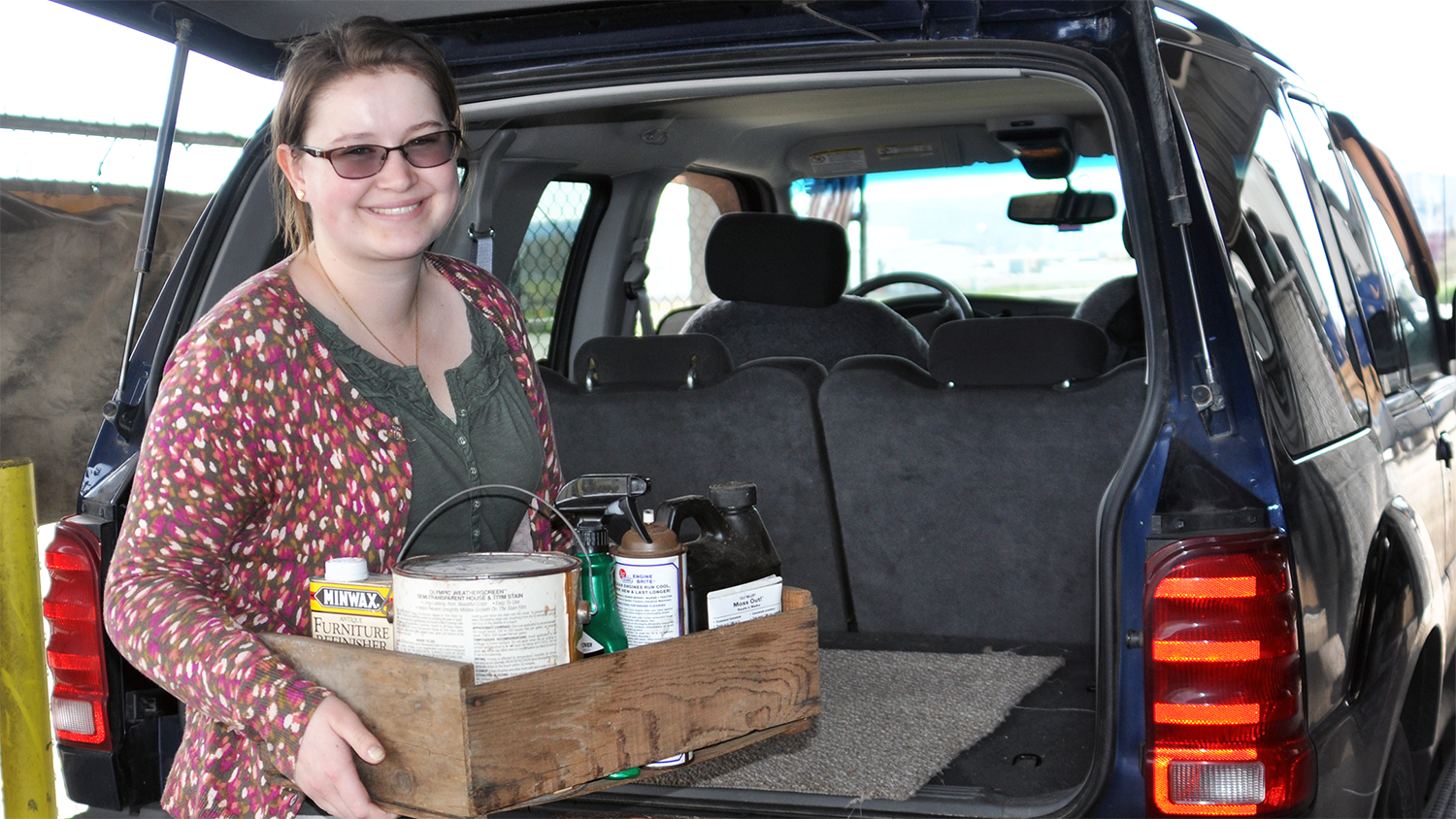 Woman is taking a box of items to a local drop-off site for proper recycling