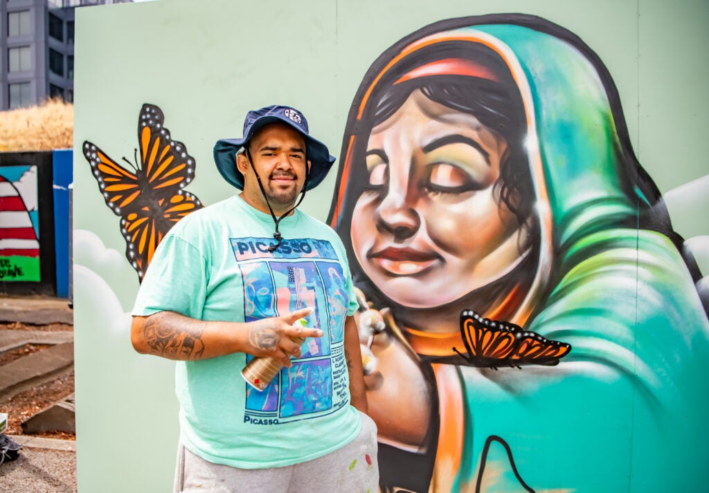 Artist stands in front of a new graffiti piece completed live during the Vancouver Arts & Music Festival
