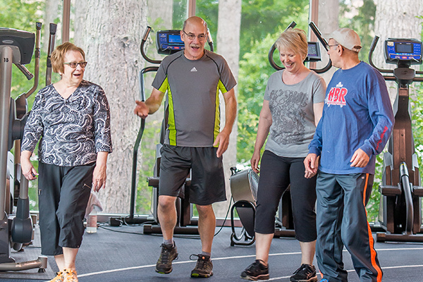 Four older adults talking and laughing while walking the indoor track at Firstenburg Community Center.