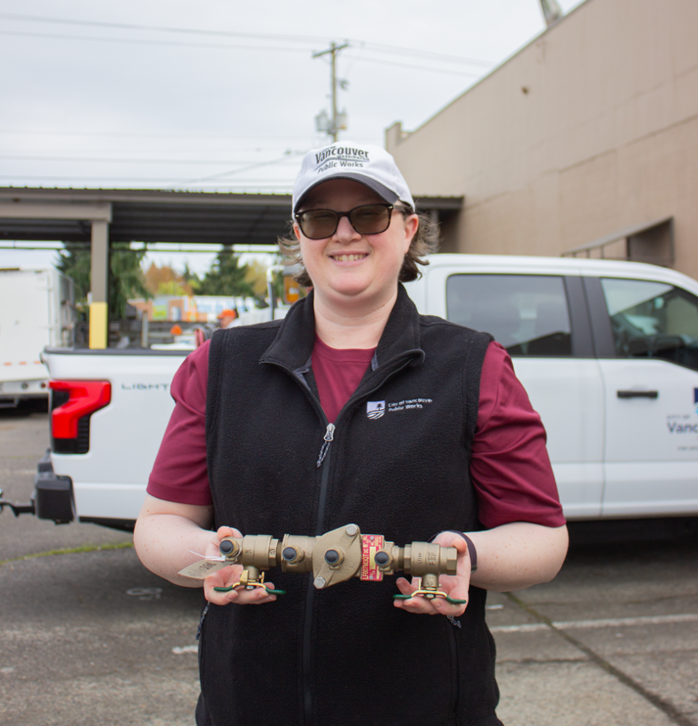 Kristi holds a backflow assembly in front of the Operations Center