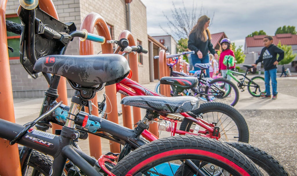Kids parking their bikes at a bike rack in front of school