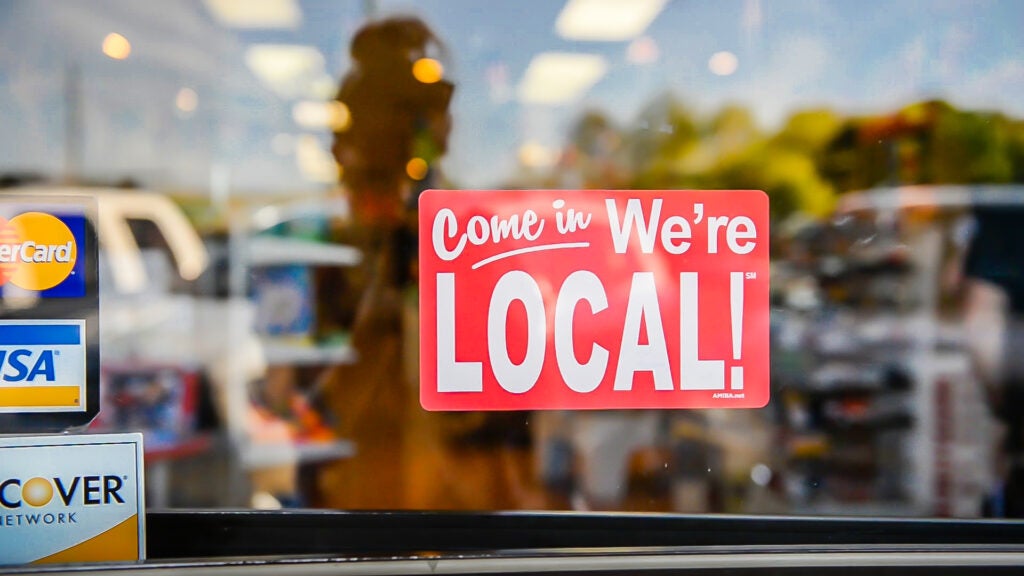 Sign in a business window that says come in we're local