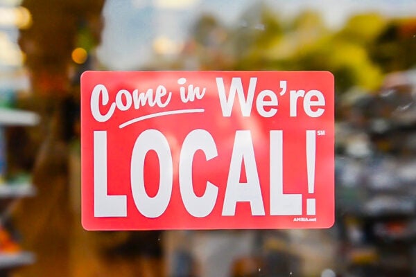 Sign in a business window that says come in we're local