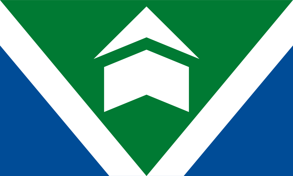 Flag shows green triangle with white V through middle of design and blue triangles on each bottom side. Angular building icon is centered inside V.