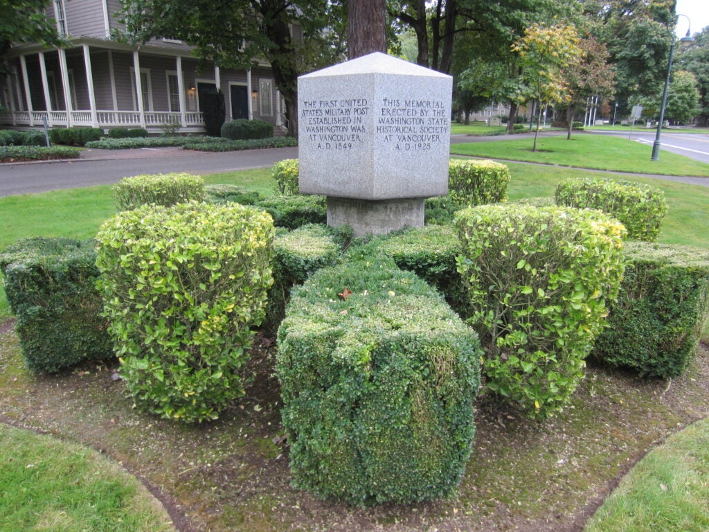 A cube shaped stone monument with writing on all sides.