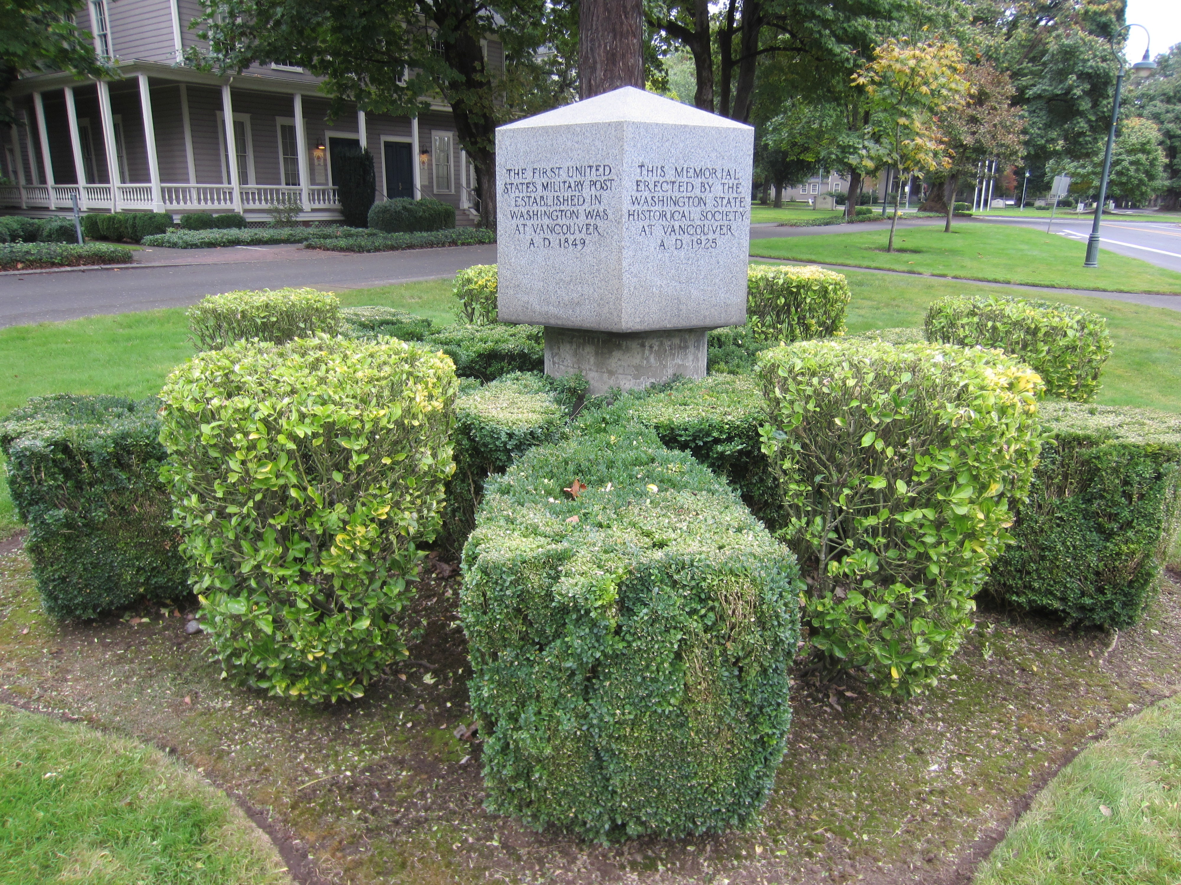 A cube shaped stone monument with writing on all sides.