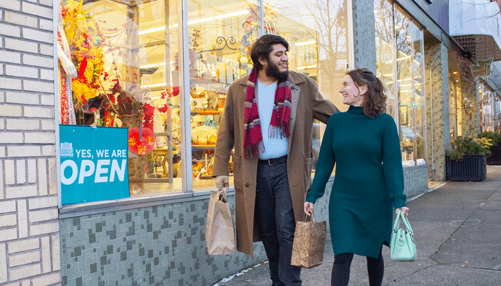 A couple walks down Main Street while holding shopping bags