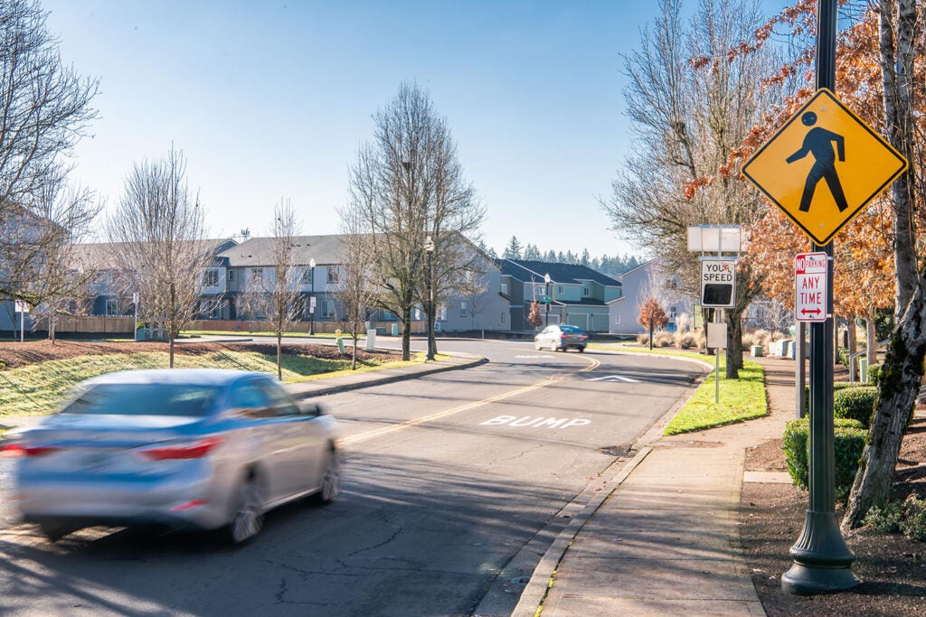 A car approaches a speed bump and speed radar feedback sign