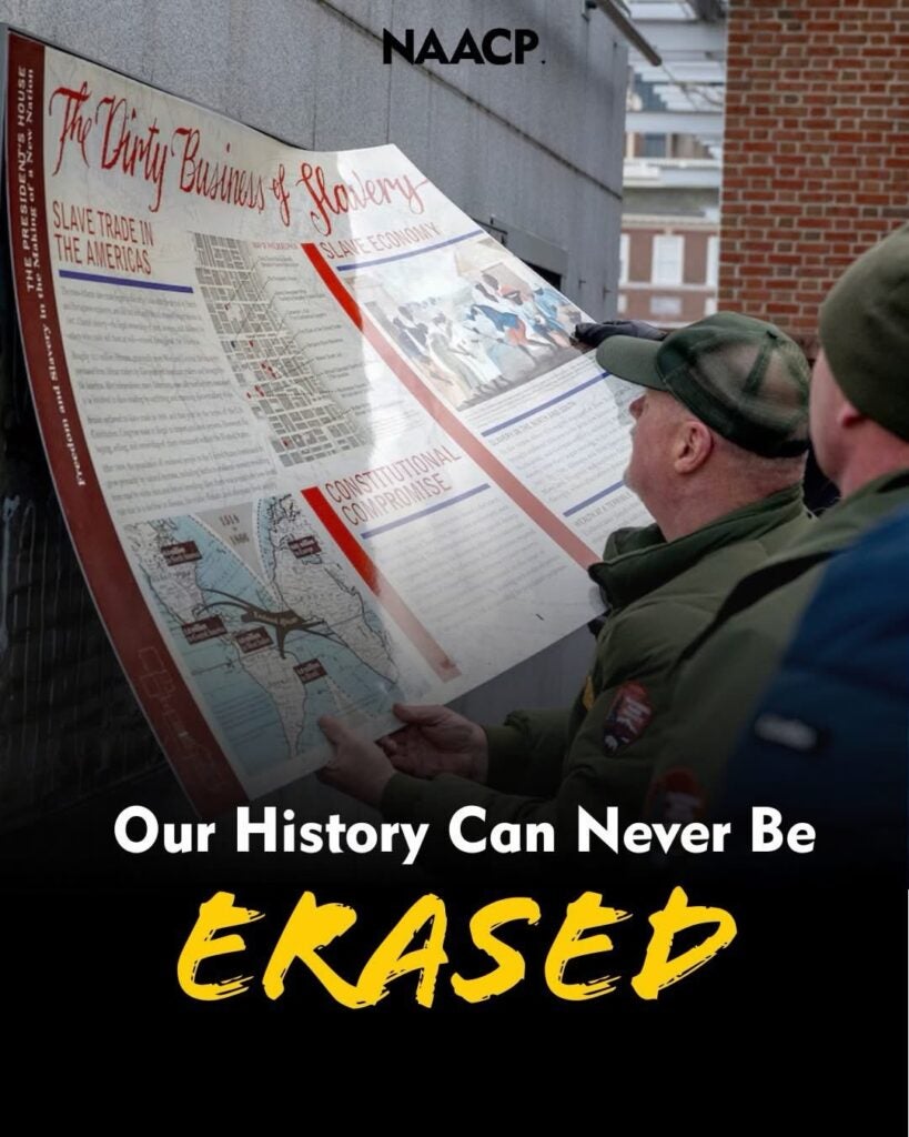 Two men hanging up display sign with words under image 