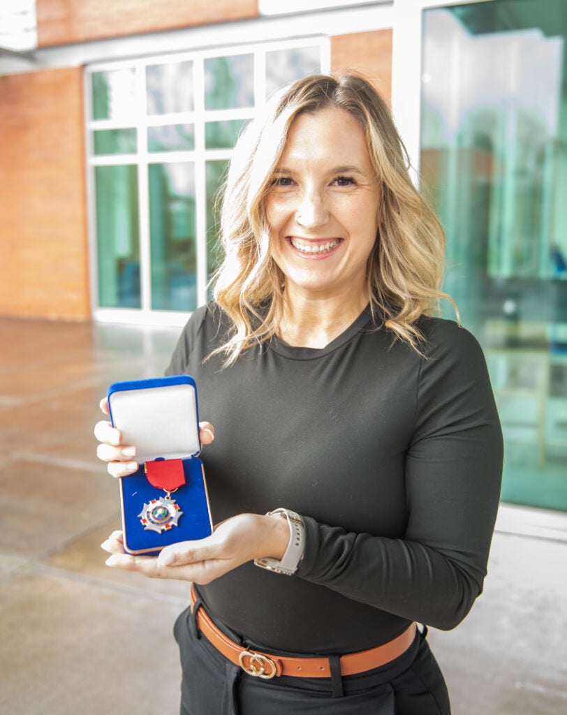 Woman holding a medal in a blue box