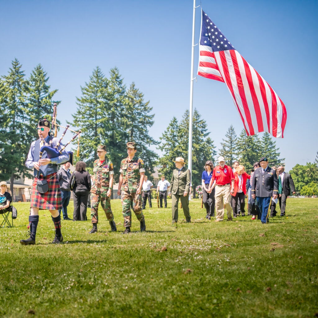 People marching in line with an American flag in the background