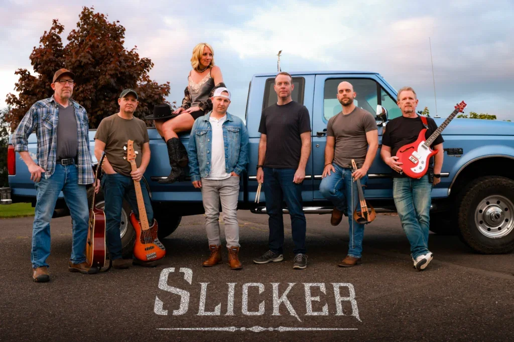 The seven band members of Slicker pose with their instruments by a pick-up truck.