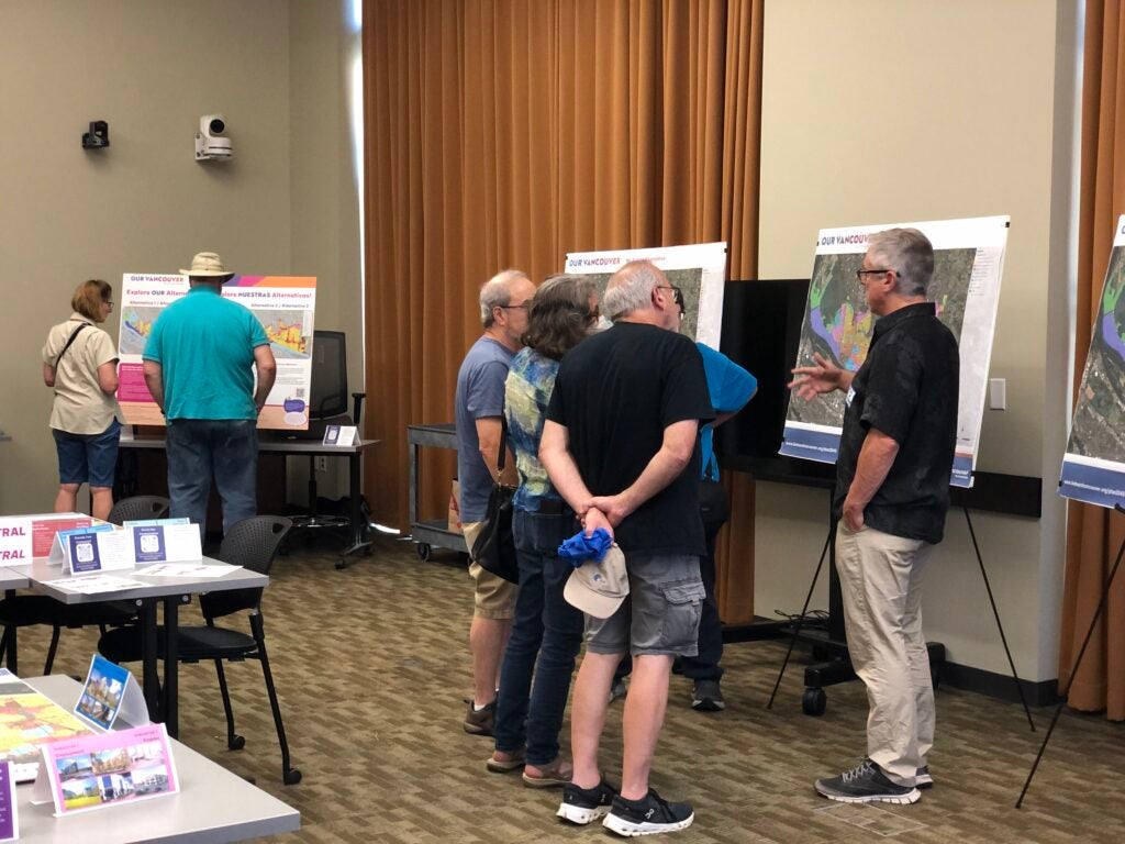 People gathered around maps on easels talking.