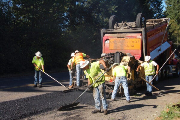 Construction workers spreading new asphalt on road.