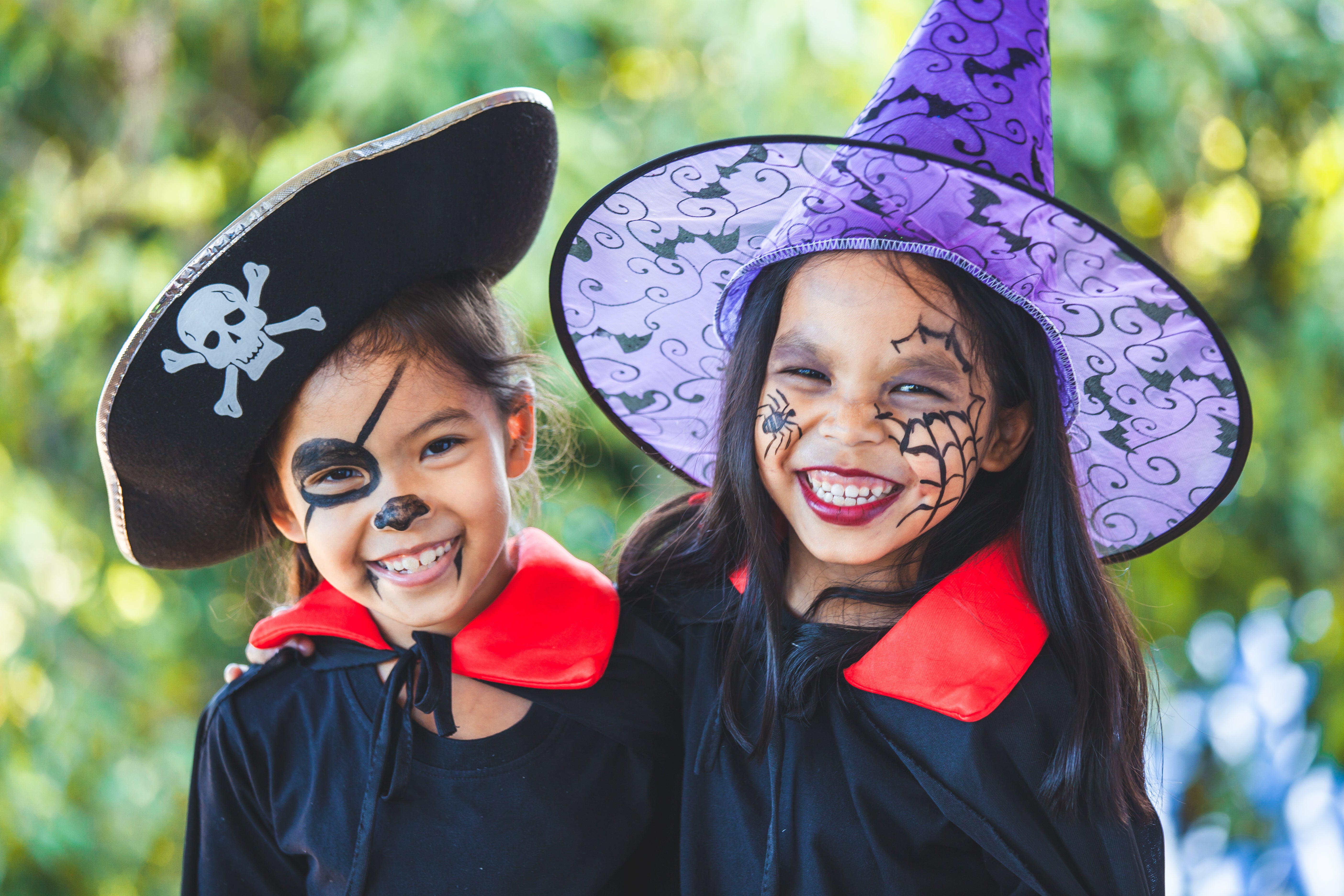 Two girls in Halloween costumes and makeup smile at the camera