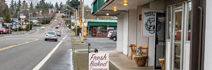 Coffee shop and sidewalk sign advertising Fresh Baked Cinnamon Rolls